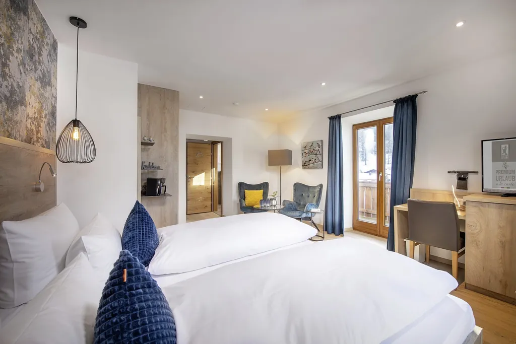 Doppelzimmer im Bayern Resort mit blauen Vorhängen und blauen Dekokissen auf dem Bett