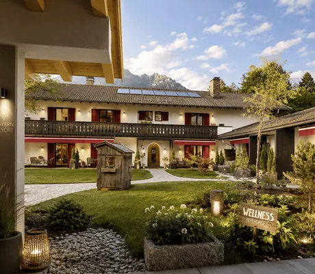 gepflegter Innenhof des Bayern Resort mit kleiner Holzhütte und Wellness-Schild