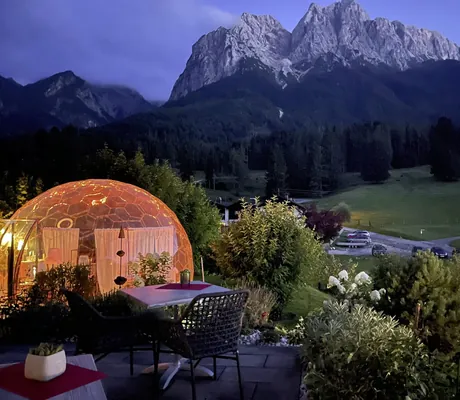 leuchtende Kugel vor der Terrasse des Bayern Resort am Abend mit Blick auf die Gebirgskette