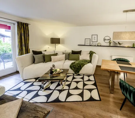 Suite mit schwarz/weißem-Designerteppich vor weißem Sofa und tannengrünem Sessel im Bayern Resort