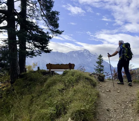 Mann mit Rucksack und Wanderstöcken wandert zu einer Bank in der Umgebung des Bayern Resort