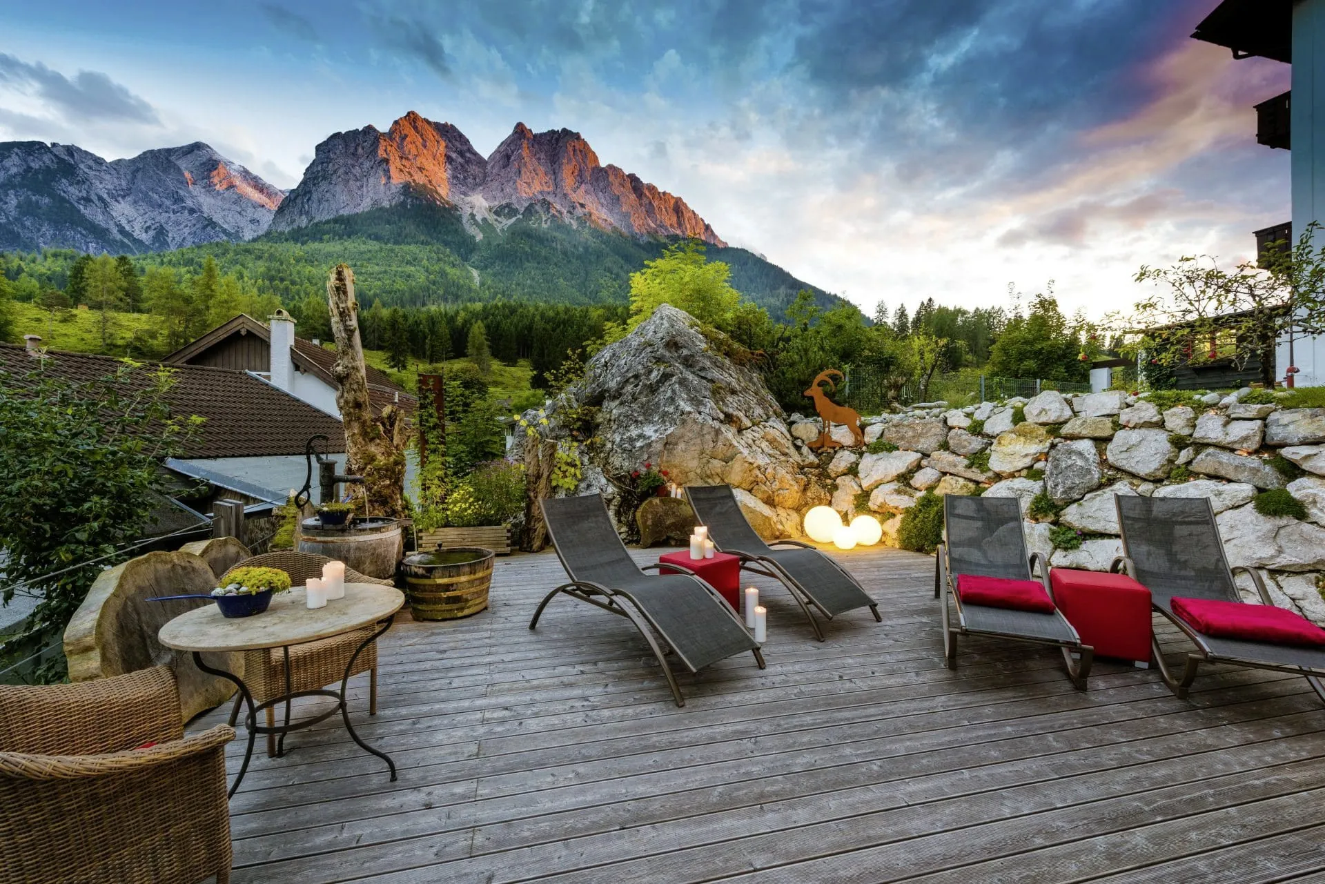Sonnenliegen mit roten Decken auf Holzterrasse des Bayern Resort vor Wettersteingebirge