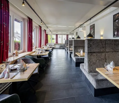 eingedeckte Tische im Restaurant des Hotel Resort Waldachtal mit grauen Polstern
