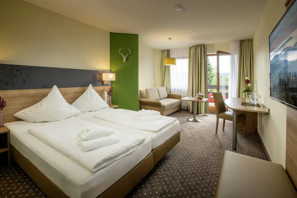 Doppelzimmer im Hotel Resort Waldachtal mit grüner Wand und Hirschgeweih